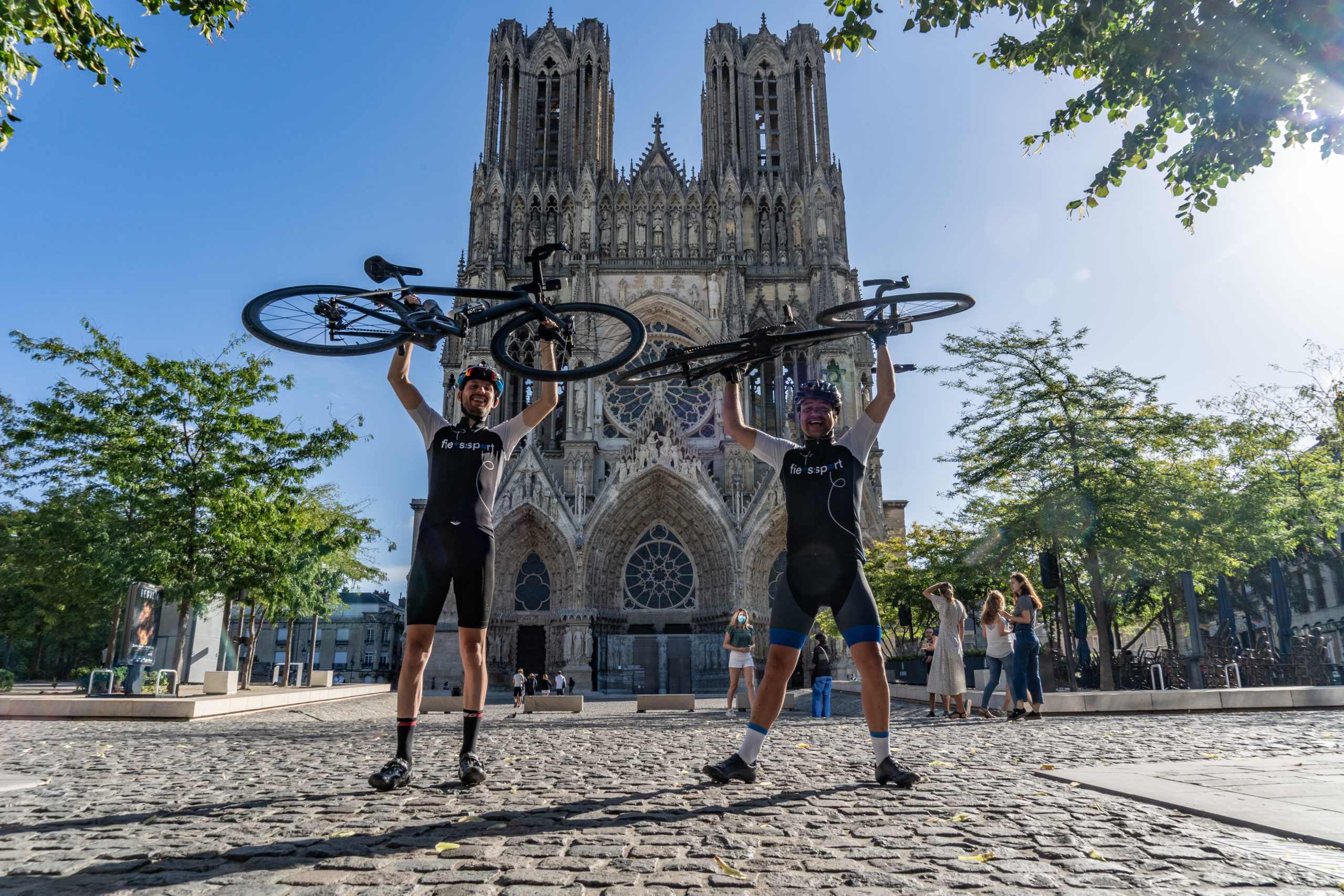 Wielrenners staan bij Kathedraal Reims met Fiets omhoog