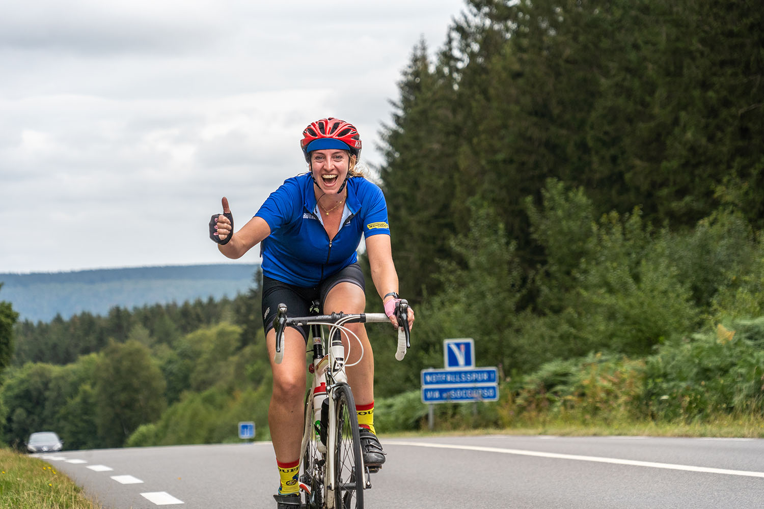 Road to Paris deelnemer lacht klimmen fiets