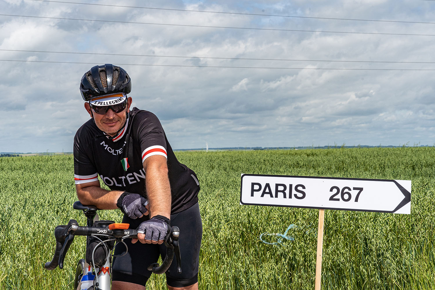 Road to Paris fietser staat naast bord paris 267 kilometer