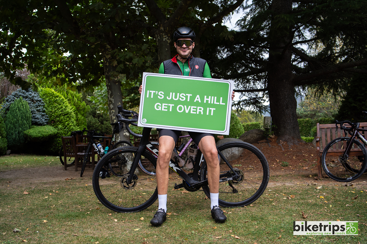 Fietser houdt bord omhoog met tekst 'it's just a hill get over it' tijdens fietsvakantie Spanje