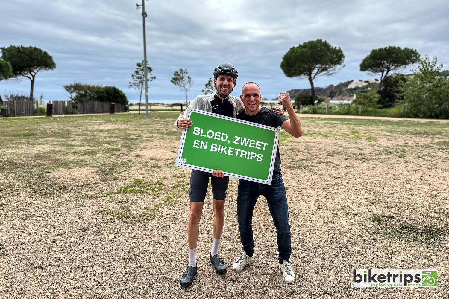 Fietsers houden bord vast met de tekst 'bloed zweet en Biketrips' tijdens fietsvakantie in Spanje