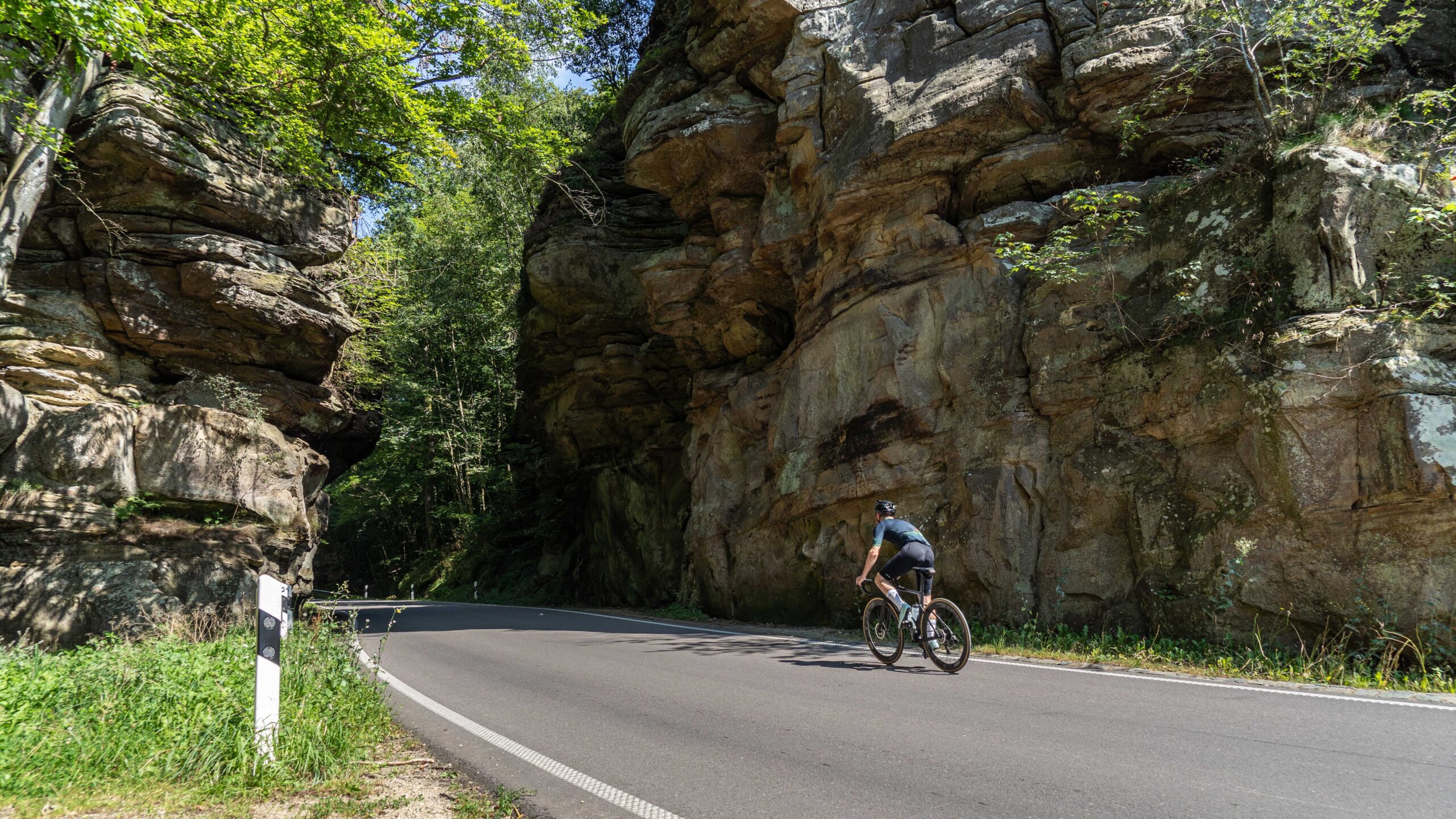 Fietser rijdt tussen de rotsen in Mullerthal Luxemburg op fietsvakantie met Biketrips