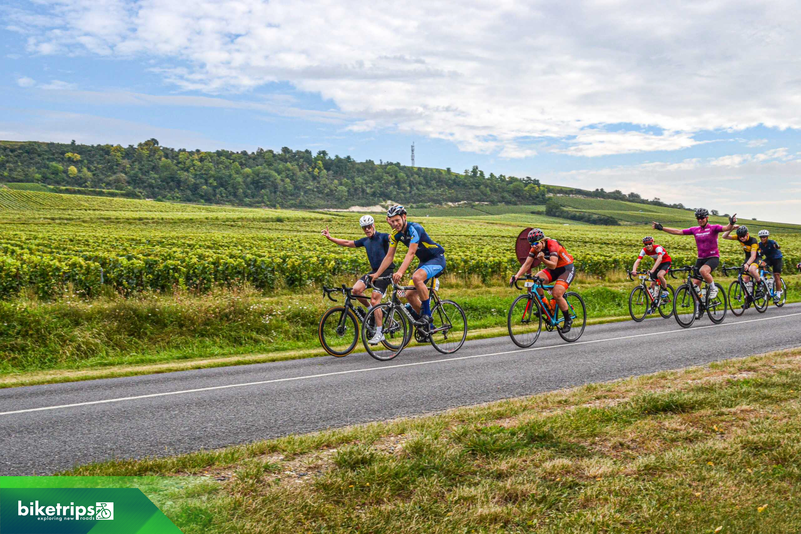 Groep fietsers komt juichend voorbij tijdens Road to Paris