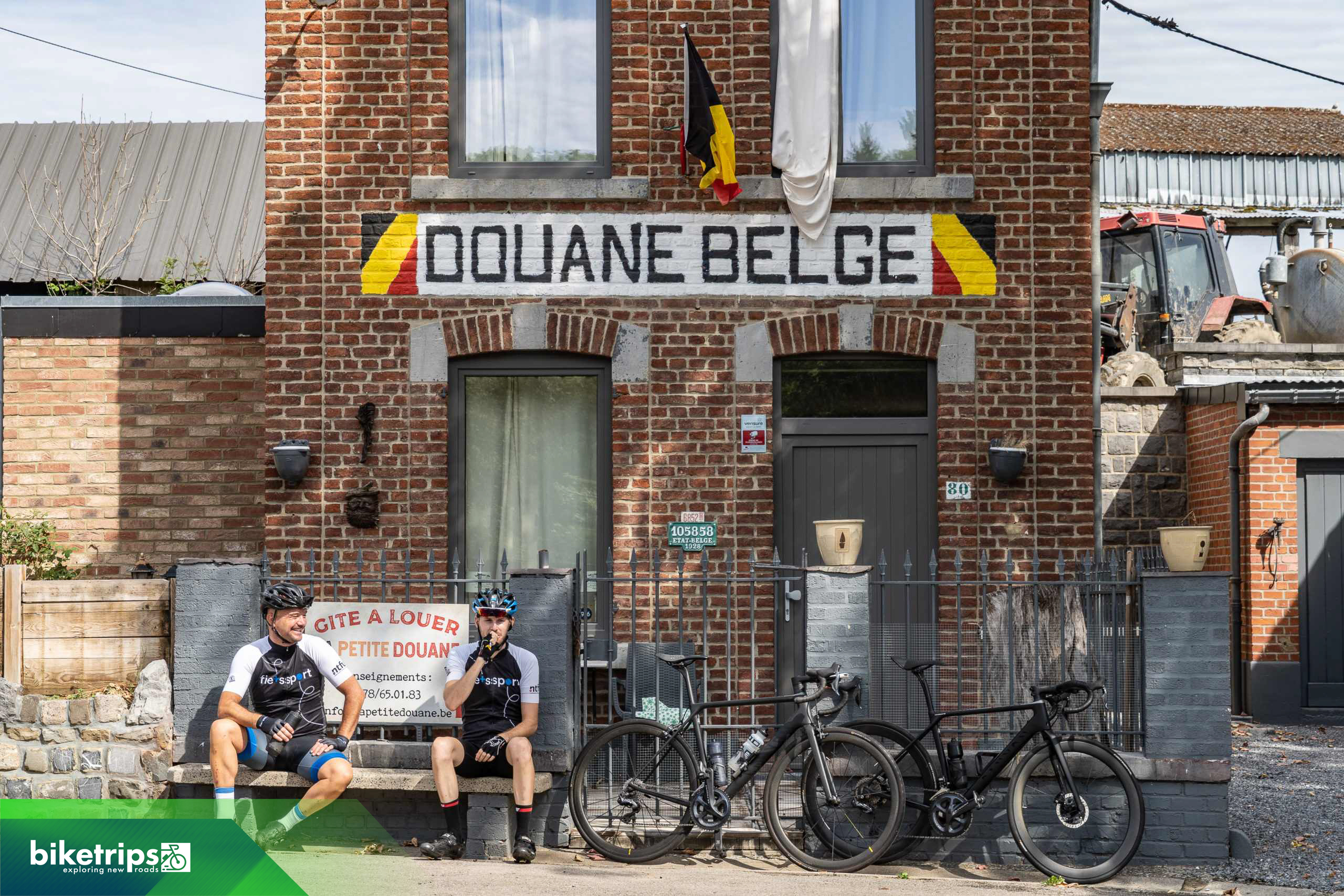 Fietsers rusten uit voor douanehuis op grens Belgie en Frankrijk op fietsvakantie