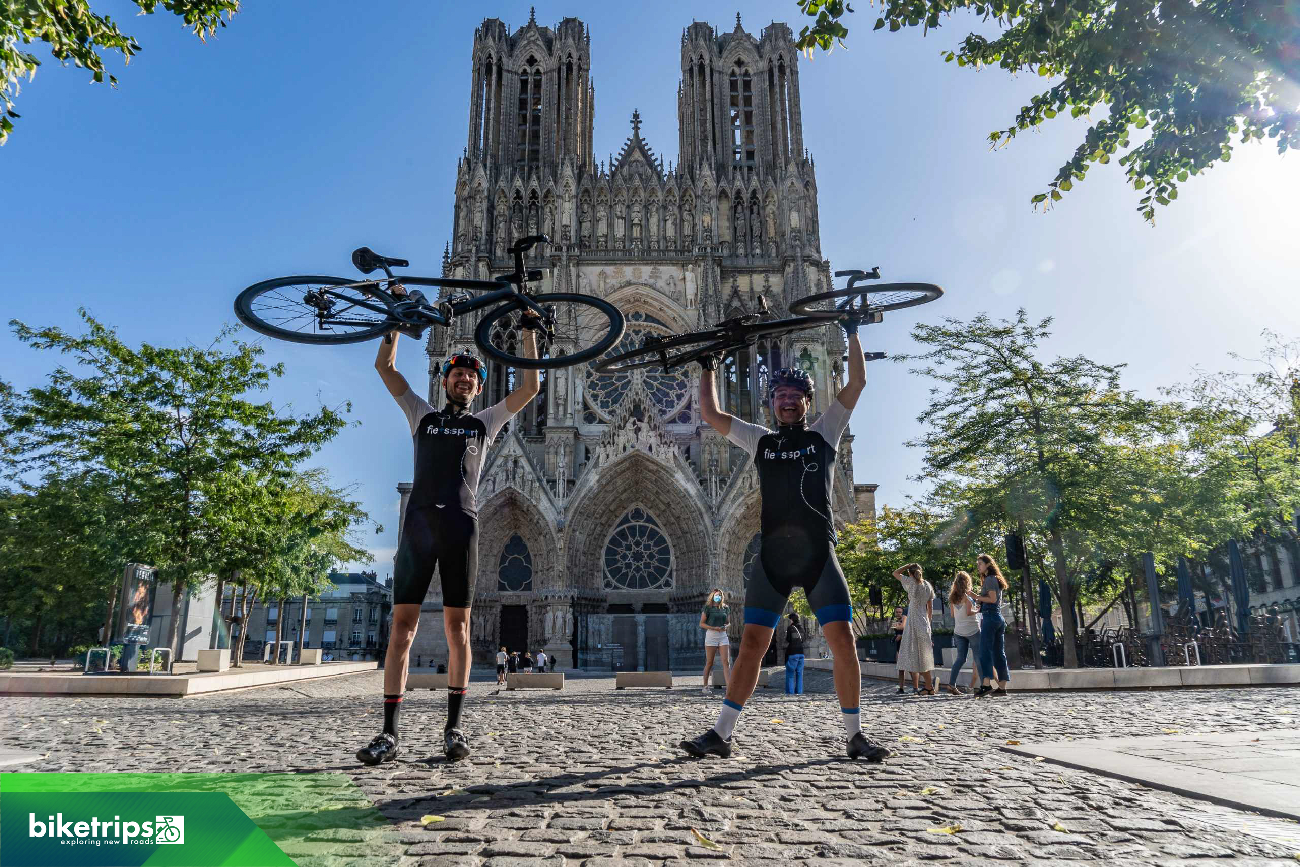 Fietsers houden hun fiets in de lucht voor de kathedraal van Reims