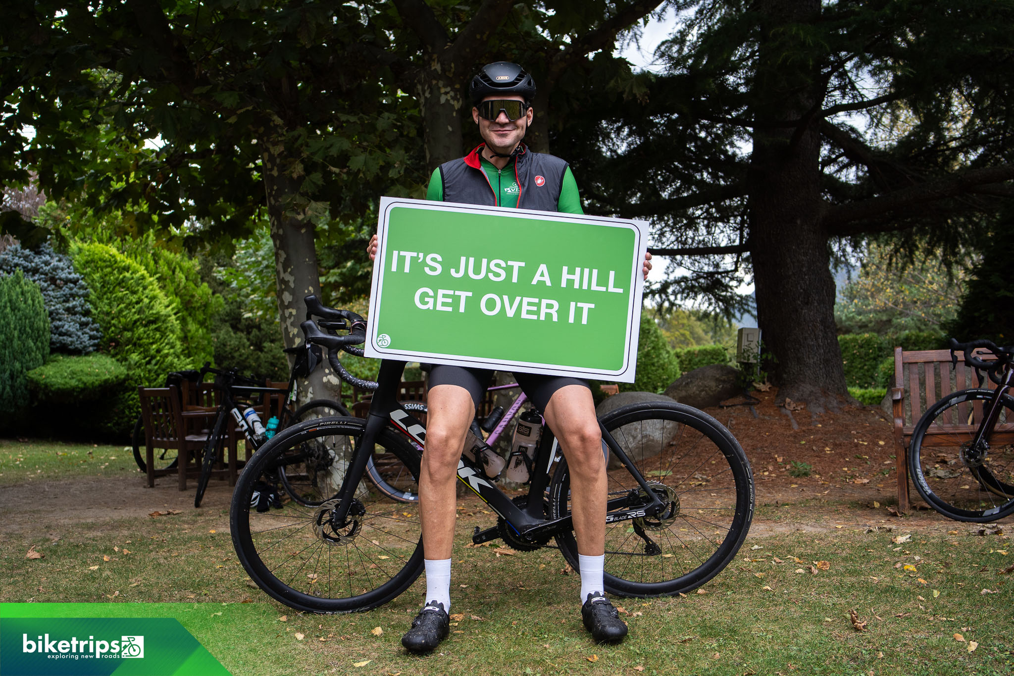 Fietser houdt bord omhoog met tekst 'it's just a hill get over it' tijdens fietsvakantie Spanje