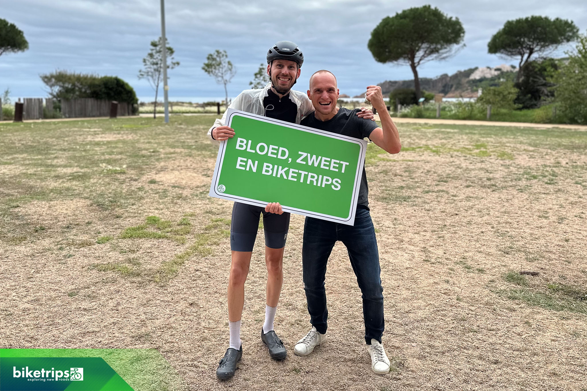 Fietsers houden bord vast met de tekst 'bloed zweet en Biketrips' tijdens fietsvakantie in Spanje