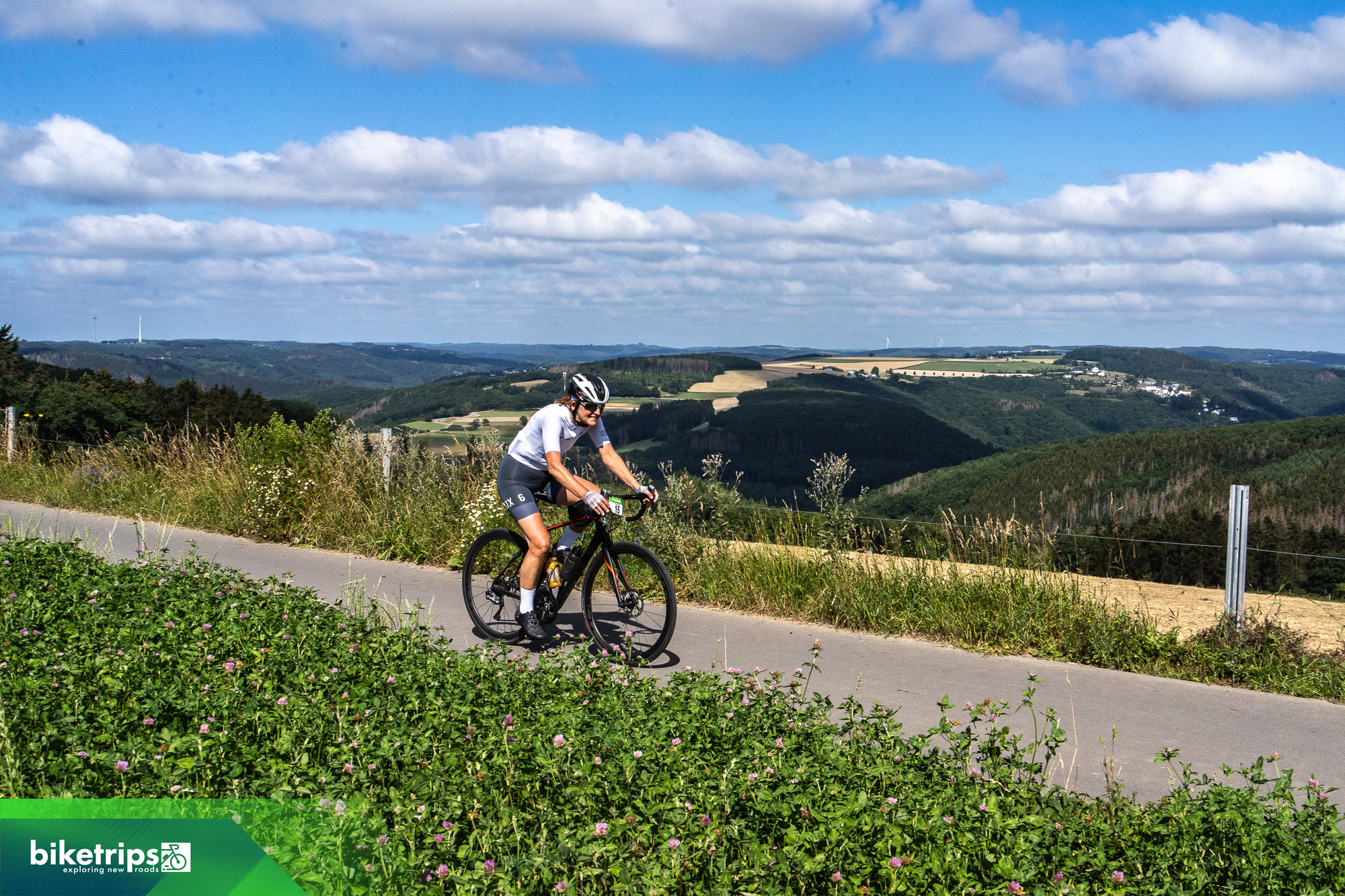 Fietser op heuveltop in Luxemburg met uitzicht over de Eislek op fietsvakantie
