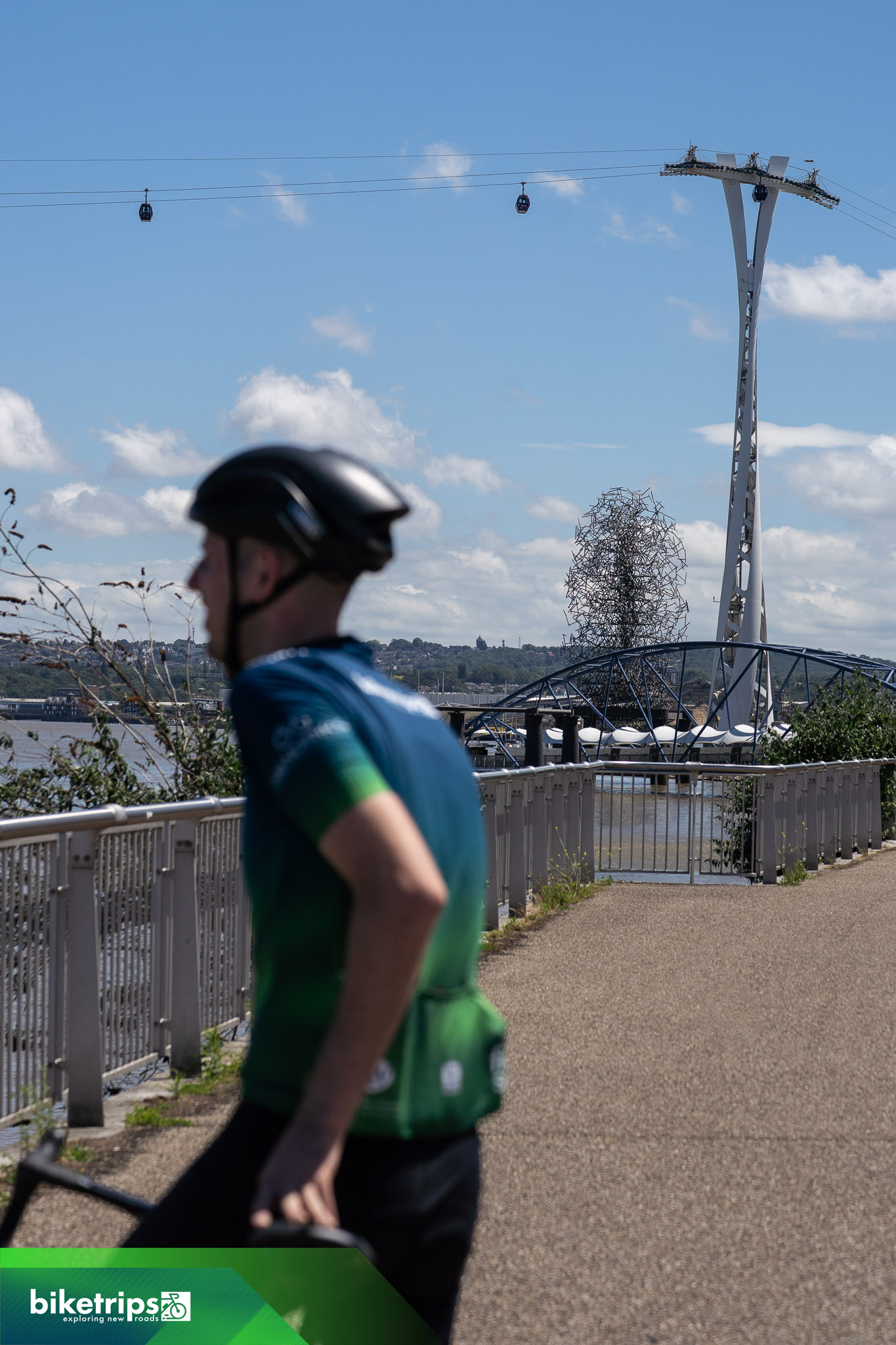 Fietser staat voor de London Cable Car langs de Theems
