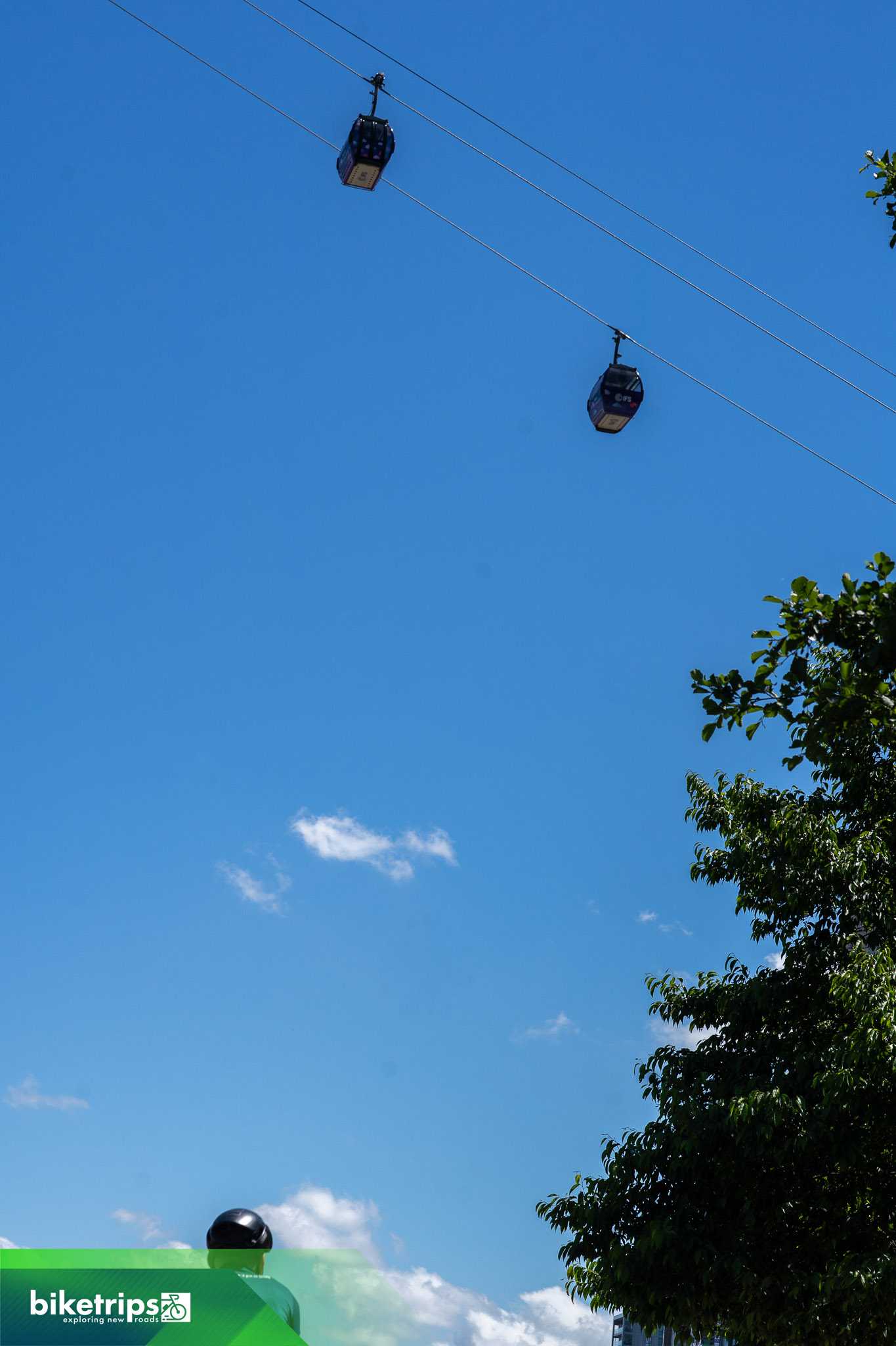 Fietser fietst onder de London Cable Car langs de Theems